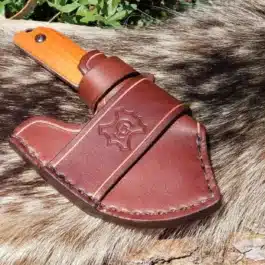 A brown Leather Scout Sheath for the Benchmade Nestucca Cleaver sitting on top of a rock.