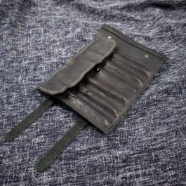 a Handmade Leather Pen Roll laying on top of a blue cloth.