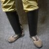 A close up of a person's legs wearing Handmade Leather Greaves.