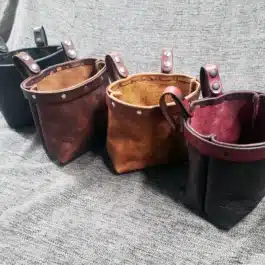 A group of four Bison leather Dump Bags sitting on top of a bed.