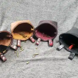 A group of Bison leather Dump Bags sitting on top of a bed.