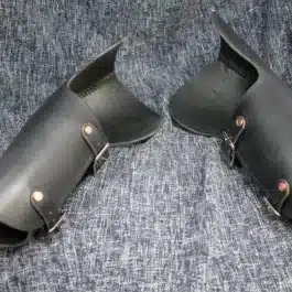 A pair of handmade black leather Bazuband Style 2 shoes on a blue cloth.