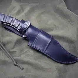 A Handmade Leather Sheath for the TOPs Longhorn Bowie that is laying on a cloth.
