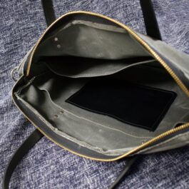 a Waxed Canvas Briefcase Satchel with a cell phone inside of it.