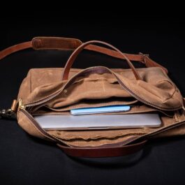 A Waxed Canvas Briefcase Satchel with a laptop inside of it.