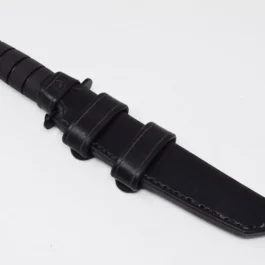 A Ka Bar Tanto Fighting Knife with a black leather sheath on a white surface.