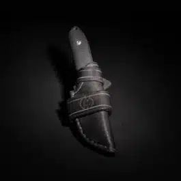 A Protech SBR with a handmade leather sheath on a black surface.