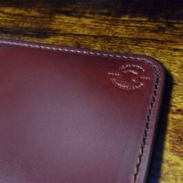 A brown Handmade Leather Mouse Pad sitting on top of a wooden table.