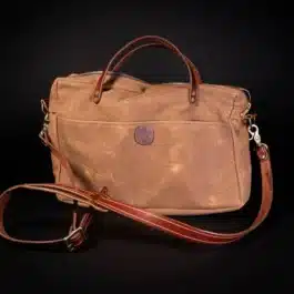 A Waxed Canvas Briefcase Satchel sitting on top of a black table.