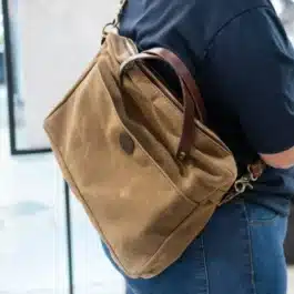 Sentence with replaced product: a person with a Waxed Canvas Briefcase Satchel on their back.