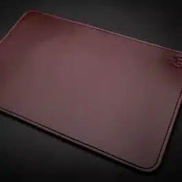 A brown leather Handmade Leather Mouse Pad on a black surface.