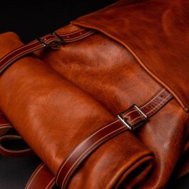 A Bison Leather Roll Top Rucksack sitting on top of a black surface.