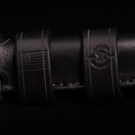 A Buck 119 knife with a handmade leather sheath on a black background.