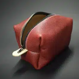 an open red Football Leather Dopp Kit/Toiletry Bag laid on a black table - renaissance clothing - renaissance clothing men - renaissance clothing women - renaissance clothing near me - renaissance art clothing - renaissance era clothing - renaissance costume ideas