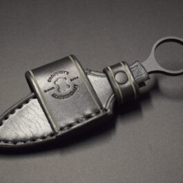 a Handmade Leather Sheath for the Benchmade Mini SOCP Dagger with a metal keyring attached to it.