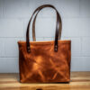 A Horween Leather Tote Bag sitting on top of a wooden table.
