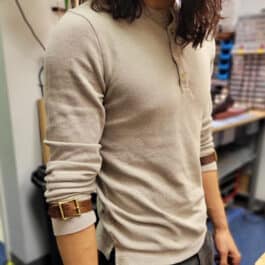 A woman standing in a room with a smile on her face, wearing Bison Leather Sleeve Garters.