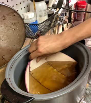 a person is removing a piece of food from a pot.
