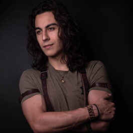 a man with long hair wearing a brown shirt and Bison Leather Sleeve Garters.