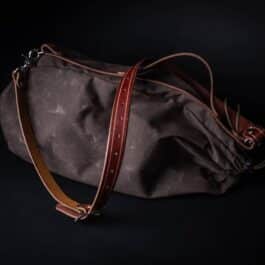 A Waxed Canvas Duffel Bag sitting on top of a black table.