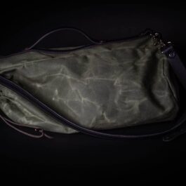 A Waxed Canvas Duffel Bag sitting on top of a black table.