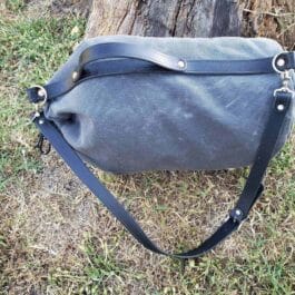 A Waxed Canvas Duffel Bag sitting on top of a grass covered field.