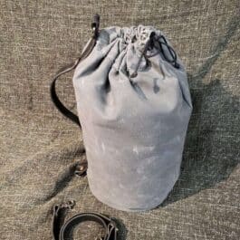 A Waxed Canvas Duffel Bag sitting on the ground next to a leash.
