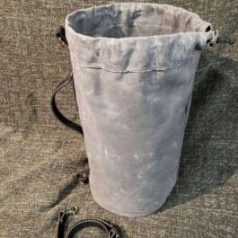 a Waxed Canvas Duffel Bag sitting on top of a floor next to a leash.