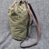 A Waxed Canvas Duffel Bag sitting on top of a gray blanket.