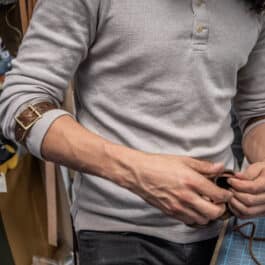 a man standing next to a table holding Bison Leather Sleeve Garters.