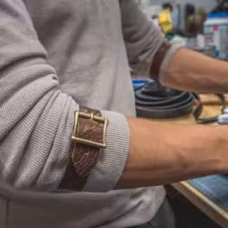 a man with grey long sleeves wearing a Bison Leather Sleeve Garters - renaissance clothing - renaissance clothing men - renaissance clothing women - renaissance clothing near me - renaissance art clothing - renaissance era clothing - renaissance costume ideas