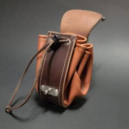 A handmade leather dice bag with a black bow.