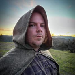 a man wearing a green wool tweed hooded cloak - renaissance clothing - renaissance clothing men - renaissance clothing women - renaissance clothing near me - renaissance art clothing - renaissance era clothing - renaissance costume ideas