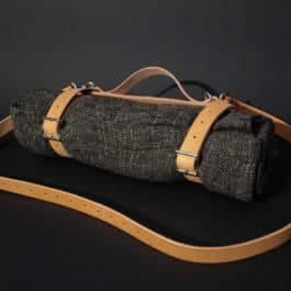 A handmade leather bedroll strap sitting on top of a table.