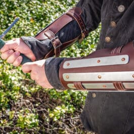 A man in a black jacket holding two Splinted Vambraces.