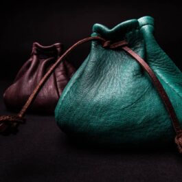 Two Leather Coin Pouches sitting side by side on a black surface.