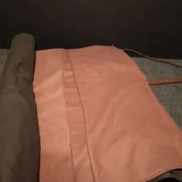 A brown and pink Ranger Bedroll sitting on top of a couch.