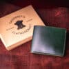 An Emerald Green Shell Cordovan Bifold Wallet sitting on top of a table.