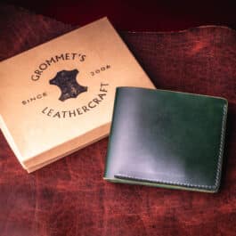An Emerald Green Shell Cordovan Bifold Wallet sitting on top of a table.