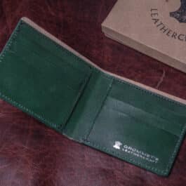 An Emerald Green Shell Cordovan Bifold Wallet sitting on top of a table.