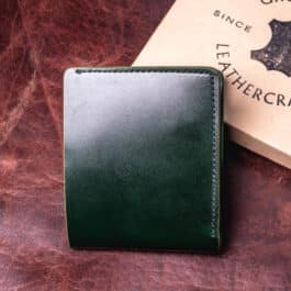 An Emerald Green Shell Cordovan Bifold Wallet sitting on top of a table.