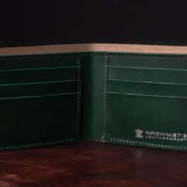 An Emerald Green Shell Cordovan Bifold Wallet sitting on top of a table.