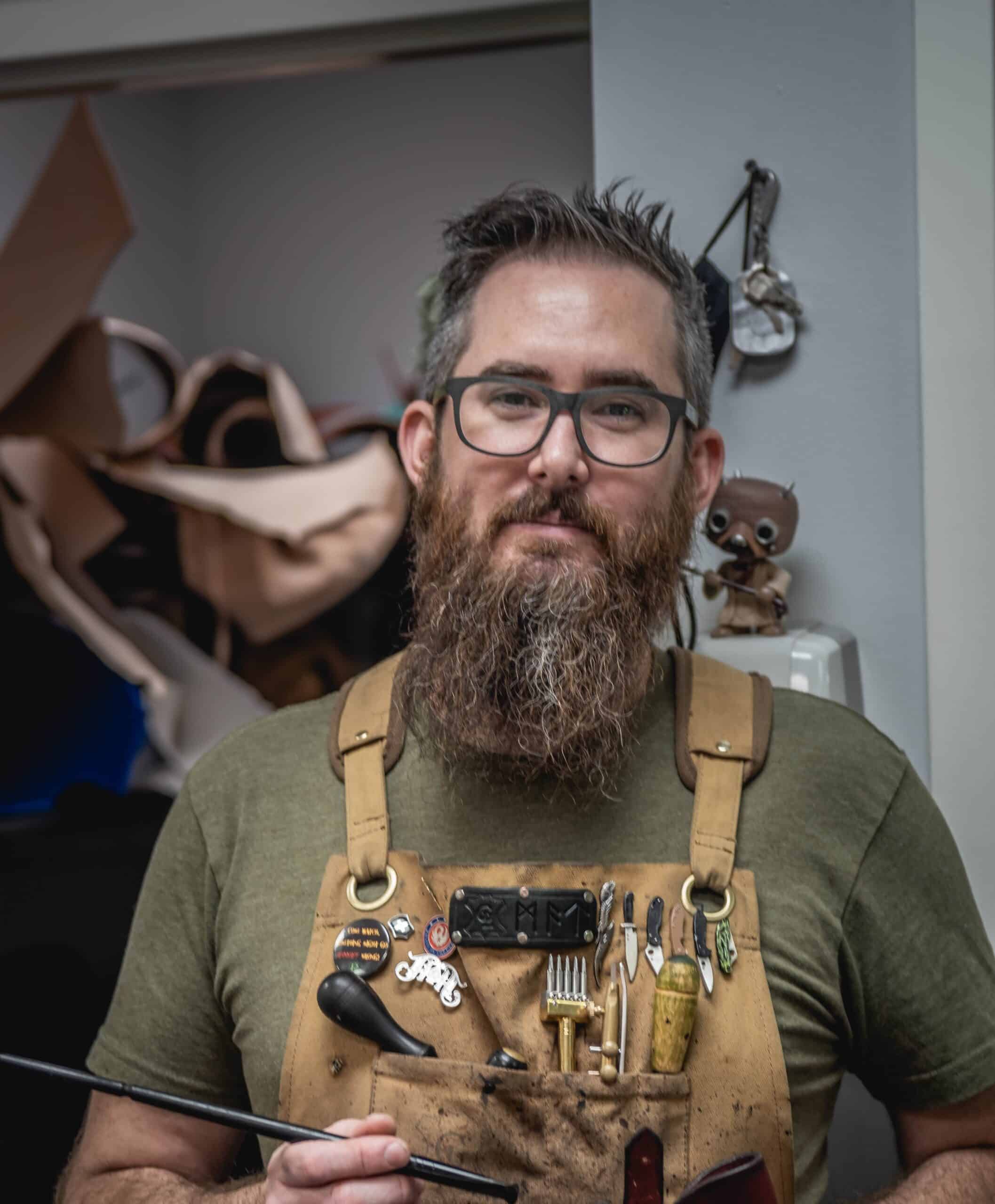 a man with a beard and glasses holding a tool.