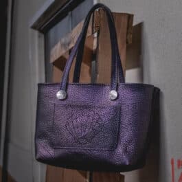 A Burgundy Mythical Koi Suede Lined Valet Tray hanging from a hook on a wall.