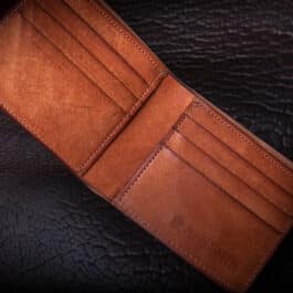 A Horween Amaretto Shell Cordovan Bifold Wallet sitting on top of a table.