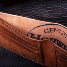 The Horween Amaretto Shell Cordovan Bifold Wallet with a logo on it.