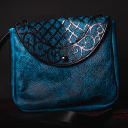 A Blue Bison Shoulder Bag with Latticework Overlay sitting on top of a wooden table.