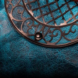 A close up of Blue Bison Shoulder Bag with Latticework Overlay on a leather surface.