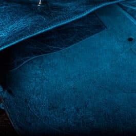 A Blue Bison Shoulder Bag with Latticework Overlay sitting on top of a table.