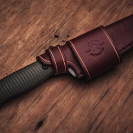 A Benchmade Anonimus knife with a Handmade Leather Sheath on a wooden table.